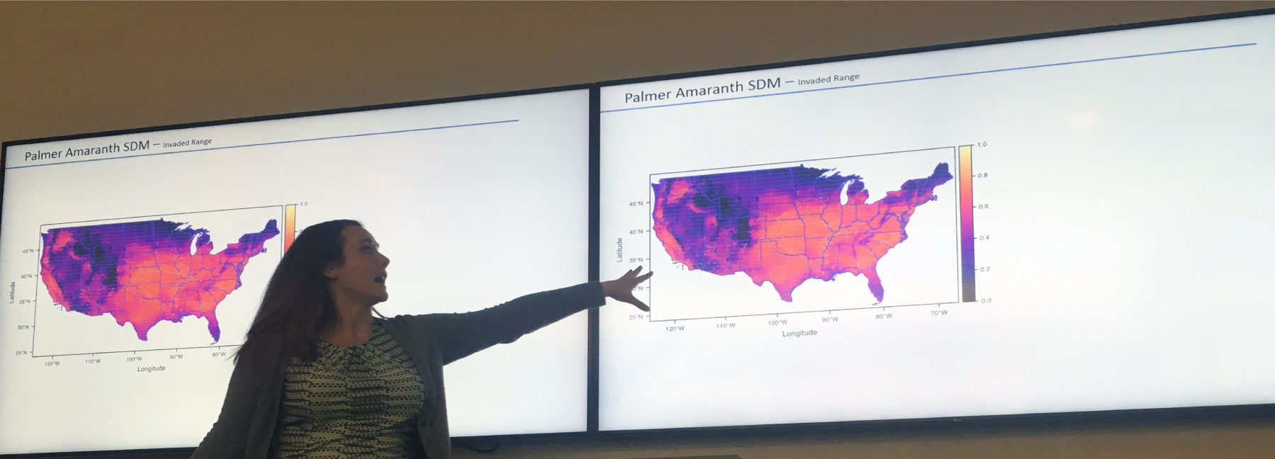 photograph of researcher in front of a wall projection of a Palmer amaranth range map of the United States